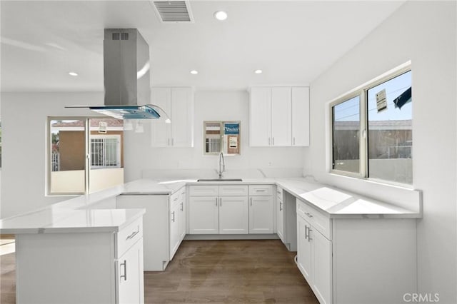 kitchen featuring sink, island range hood, white cabinets, and kitchen peninsula