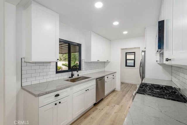 kitchen featuring sink, appliances with stainless steel finishes, white cabinetry, backsplash, and light stone countertops