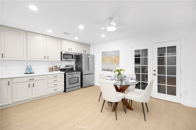 kitchen featuring appliances with stainless steel finishes, white cabinetry, ceiling fan, light hardwood / wood-style floors, and french doors