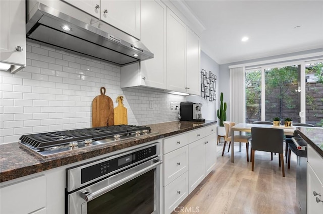 kitchen with ventilation hood, appliances with stainless steel finishes, and white cabinets