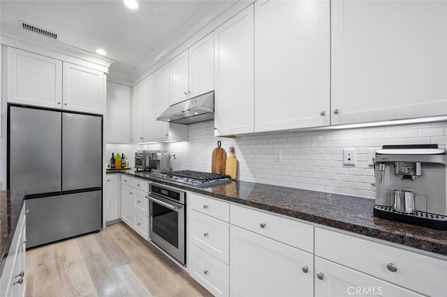 kitchen featuring dark stone countertops, stainless steel appliances, and white cabinets