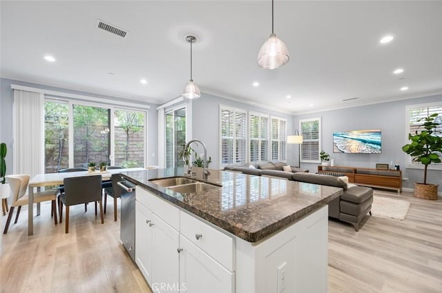 kitchen with sink, decorative light fixtures, an island with sink, light hardwood / wood-style floors, and white cabinets