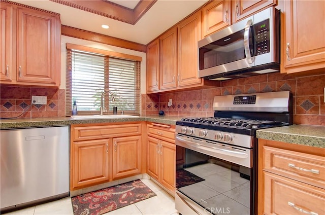 kitchen with tasteful backsplash, appliances with stainless steel finishes, sink, and light tile patterned floors