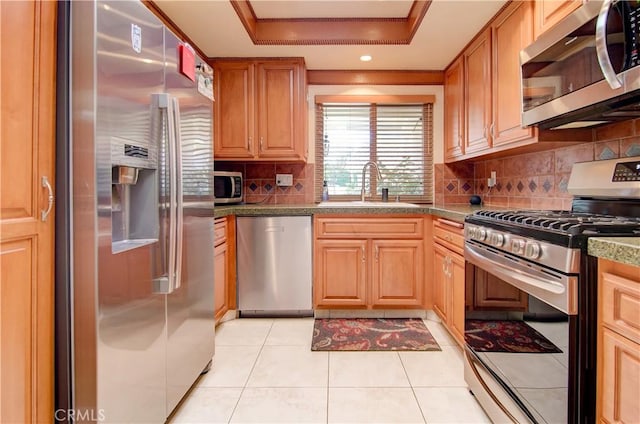 kitchen featuring sink, light tile patterned floors, stainless steel appliances, tasteful backsplash, and a raised ceiling