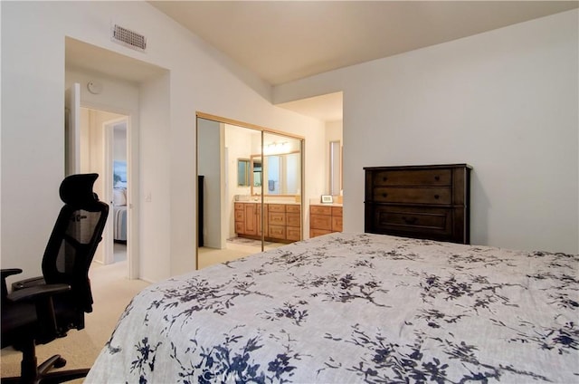 carpeted bedroom with ensuite bathroom, vaulted ceiling, and a closet