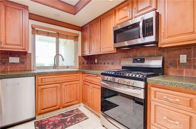 kitchen featuring light tile patterned floors, appliances with stainless steel finishes, a sink, and tasteful backsplash