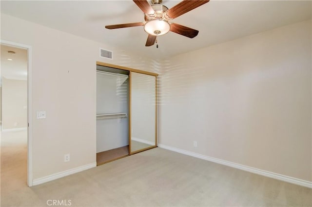 unfurnished bedroom featuring light colored carpet, a ceiling fan, baseboards, visible vents, and a closet