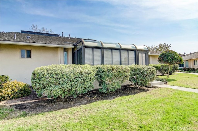 view of side of property featuring a lawn and stucco siding