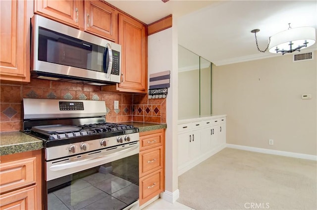 kitchen featuring appliances with stainless steel finishes, dark countertops, visible vents, and crown molding