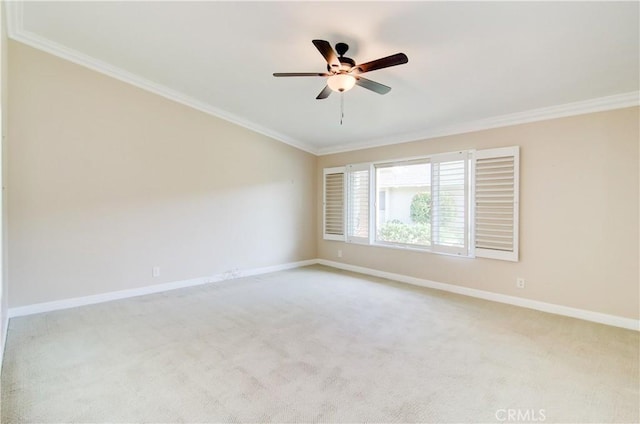 spare room featuring light colored carpet, crown molding, baseboards, and ceiling fan