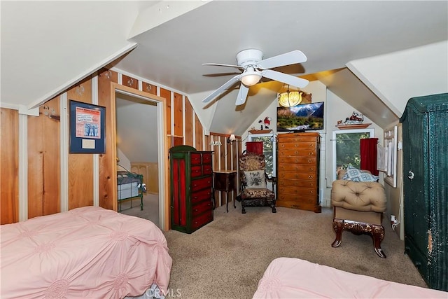 carpeted bedroom featuring vaulted ceiling, ceiling fan, and wood walls