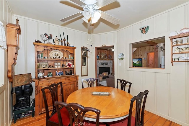 dining space featuring a fireplace, light hardwood / wood-style floors, and ceiling fan