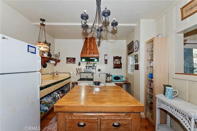 kitchen with a kitchen island, white fridge, a chandelier, and built in shelves