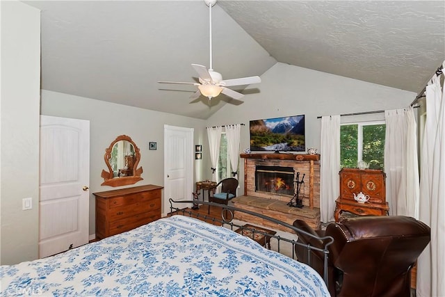 bedroom featuring vaulted ceiling, a textured ceiling, a fireplace, and ceiling fan