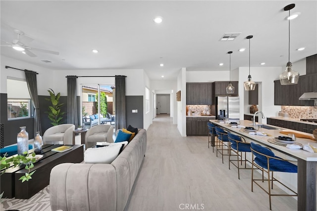 living room with sink, ceiling fan, and light hardwood / wood-style flooring