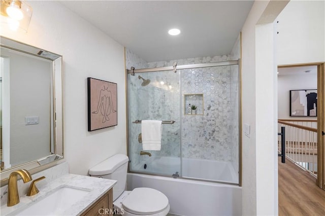 full bathroom featuring vanity, hardwood / wood-style flooring, enclosed tub / shower combo, and toilet