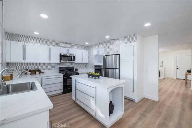 kitchen with sink, white cabinetry, a kitchen island, stainless steel appliances, and decorative backsplash