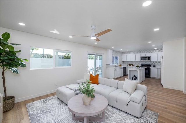 living room featuring ceiling fan, a healthy amount of sunlight, and light wood-type flooring