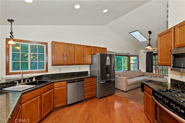 kitchen featuring pendant lighting, sink, appliances with stainless steel finishes, high vaulted ceiling, and light wood-type flooring