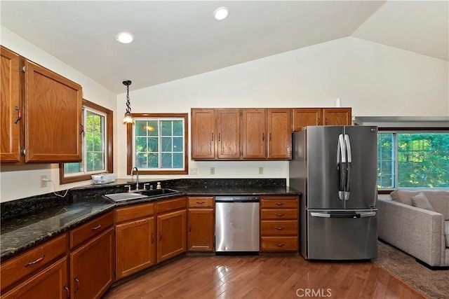 kitchen with dark wood-type flooring, sink, vaulted ceiling, hanging light fixtures, and stainless steel appliances