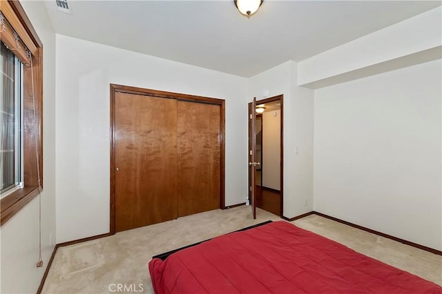 unfurnished bedroom with light colored carpet and a closet