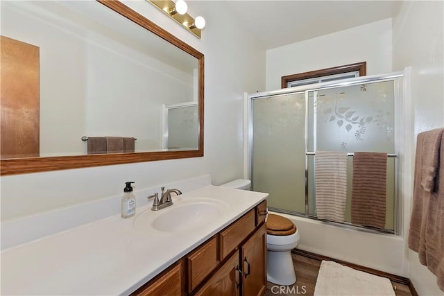 full bathroom featuring vanity, wood-type flooring, shower / bath combination with glass door, and toilet