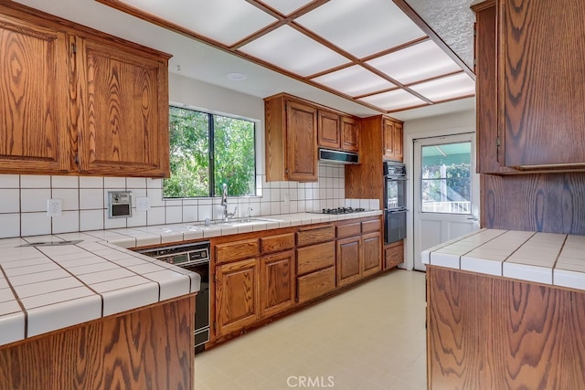 kitchen with tile counters, sink, decorative backsplash, and black appliances