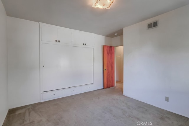 unfurnished bedroom featuring light carpet and a closet