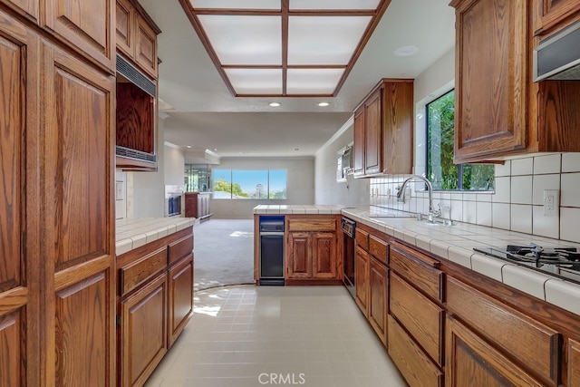 kitchen with sink, gas cooktop, tasteful backsplash, tile countertops, and kitchen peninsula