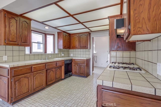 kitchen with white gas stovetop, tile counters, dishwasher, and decorative backsplash