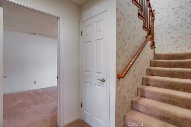 stairway featuring carpet floors and a textured ceiling