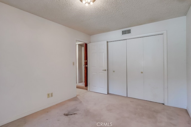 unfurnished bedroom featuring light carpet, a textured ceiling, and a closet