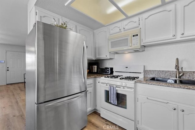 kitchen with sink, white appliances, light hardwood / wood-style floors, and white cabinets