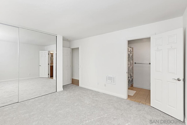 unfurnished bedroom with light colored carpet, ensuite bath, and a closet