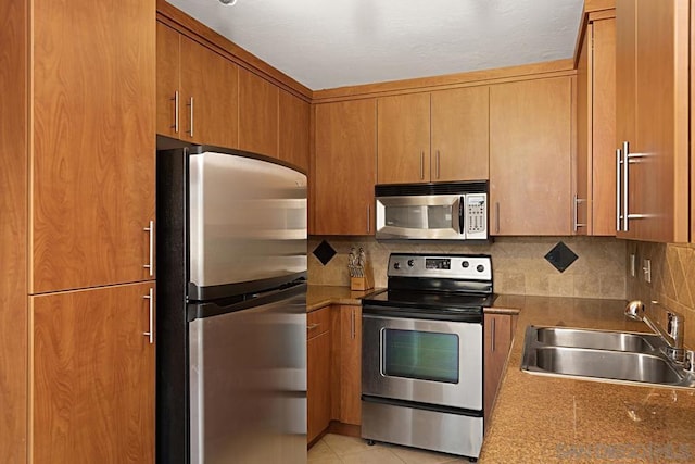 kitchen with light tile patterned flooring, appliances with stainless steel finishes, sink, and decorative backsplash