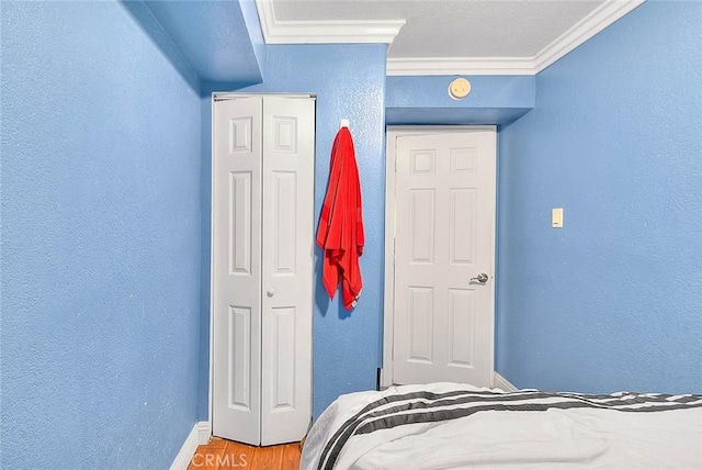 bedroom featuring hardwood / wood-style flooring, ornamental molding, and a closet