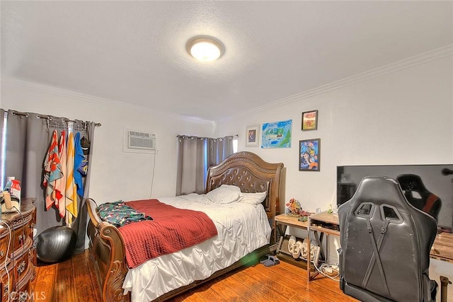 bedroom with hardwood / wood-style flooring, crown molding, an AC wall unit, and a textured ceiling