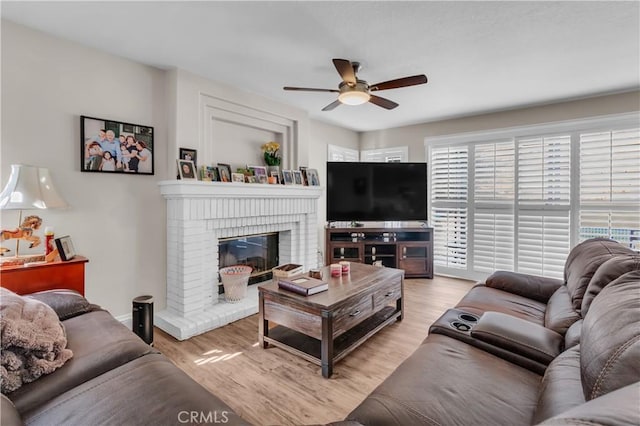 living room featuring a fireplace, light hardwood / wood-style flooring, and ceiling fan