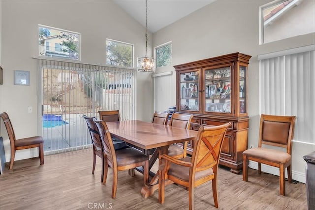 dining space featuring an inviting chandelier, high vaulted ceiling, and light hardwood / wood-style floors