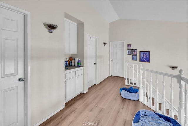 hall with lofted ceiling and light hardwood / wood-style floors