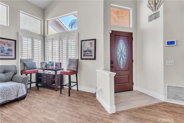 entryway with light hardwood / wood-style floors and a high ceiling