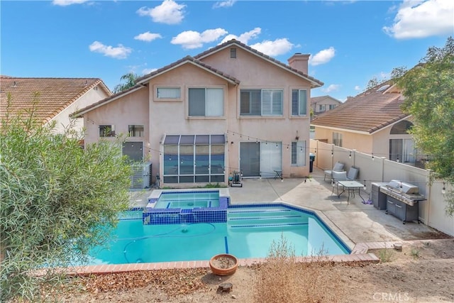 rear view of property featuring a swimming pool with hot tub and a patio area