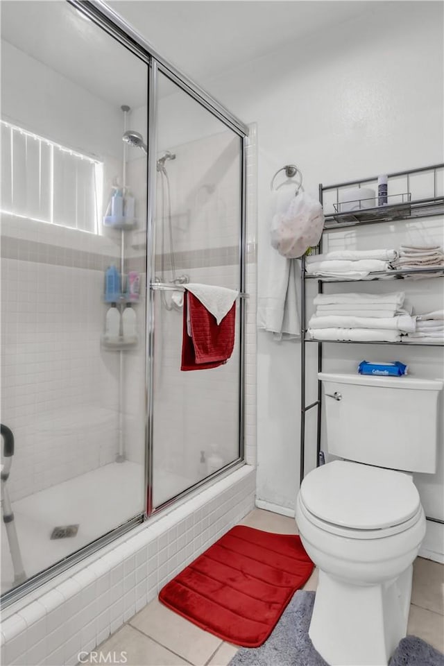 bathroom with toilet, tile patterned floors, and a shower with shower door