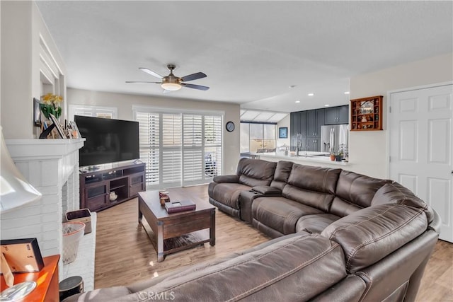 living room with sink, light hardwood / wood-style flooring, and ceiling fan