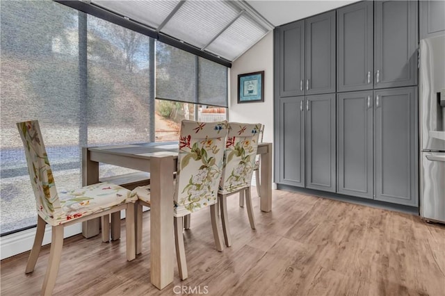 dining space featuring vaulted ceiling and light wood-type flooring