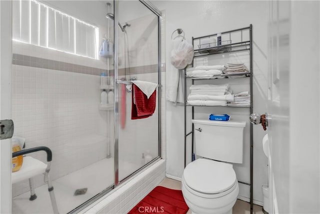 bathroom featuring a shower with door and toilet