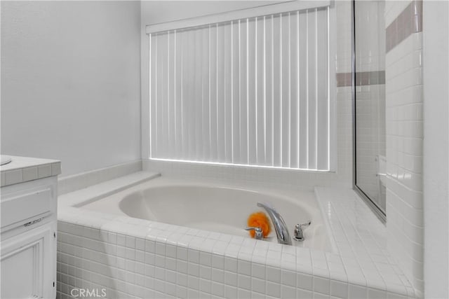 bathroom with vanity and tiled bath