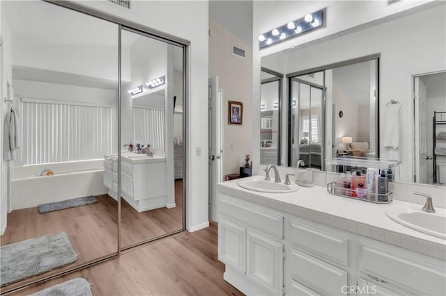 bathroom featuring wood-type flooring, vanity, and a washtub