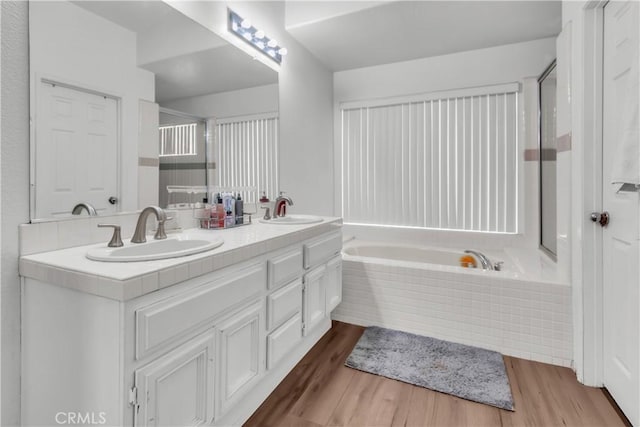 bathroom with vanity, wood-type flooring, and tiled bath