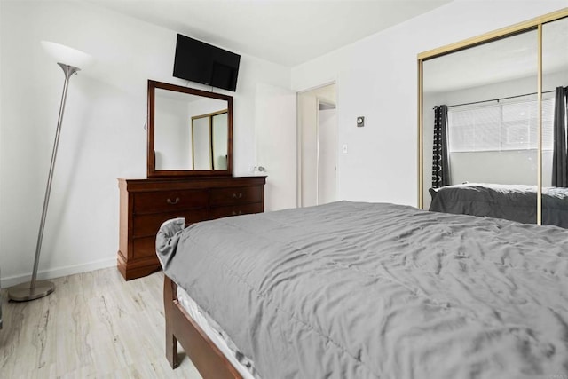 bedroom with light hardwood / wood-style floors and a closet